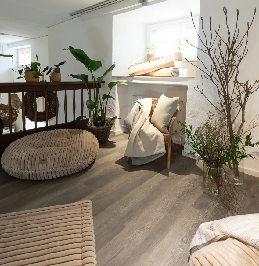 Sitzecke mit Sitzsack, Decken und Zweigen vor weißer Wand