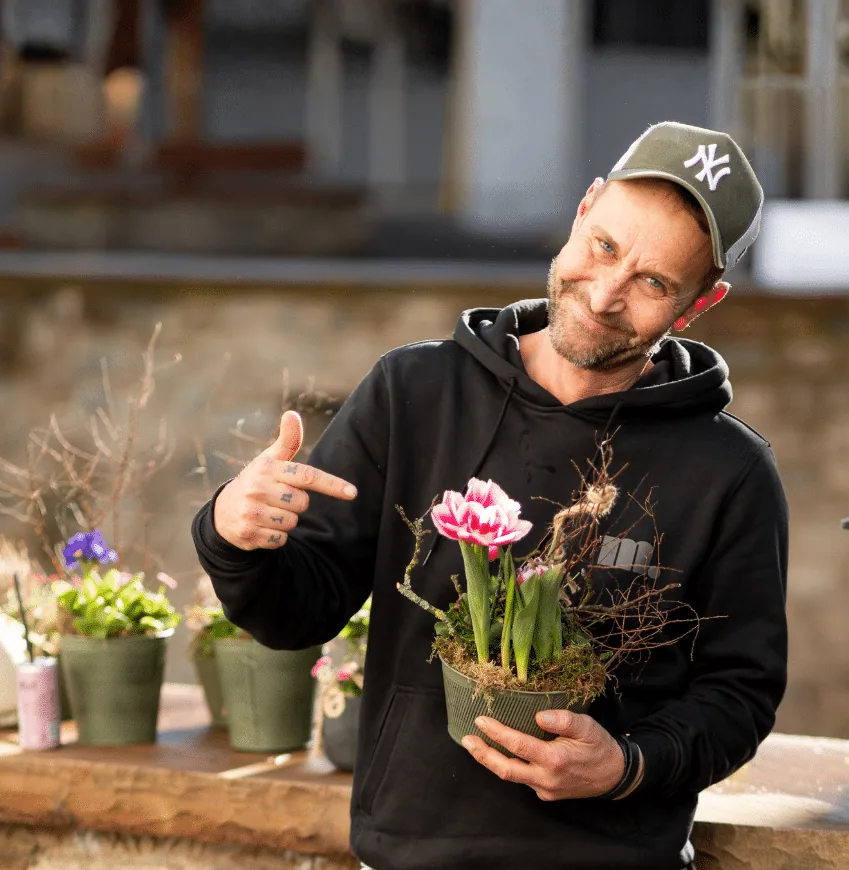 Markus Lauscher hält lachend einen bepflanzten Topf mit Tulpen in die Kamera